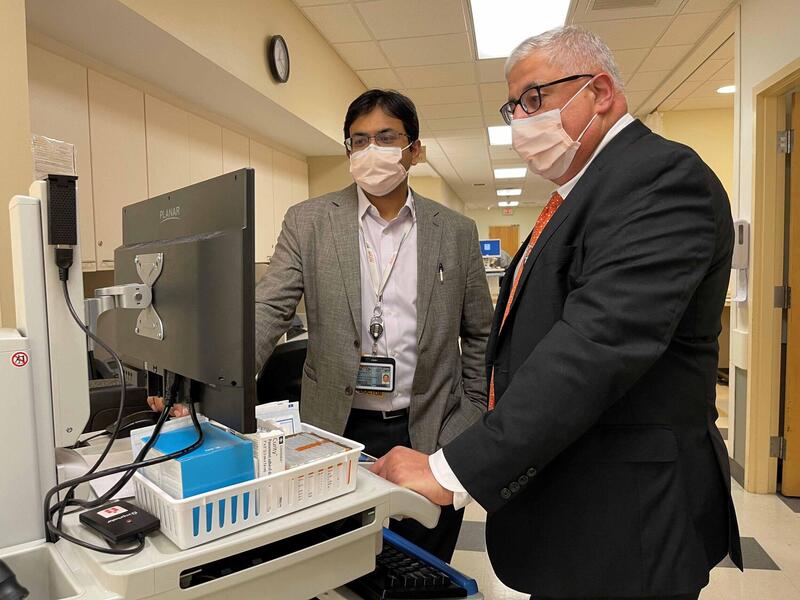 two men standing in a medical facility and looking at a computer screen