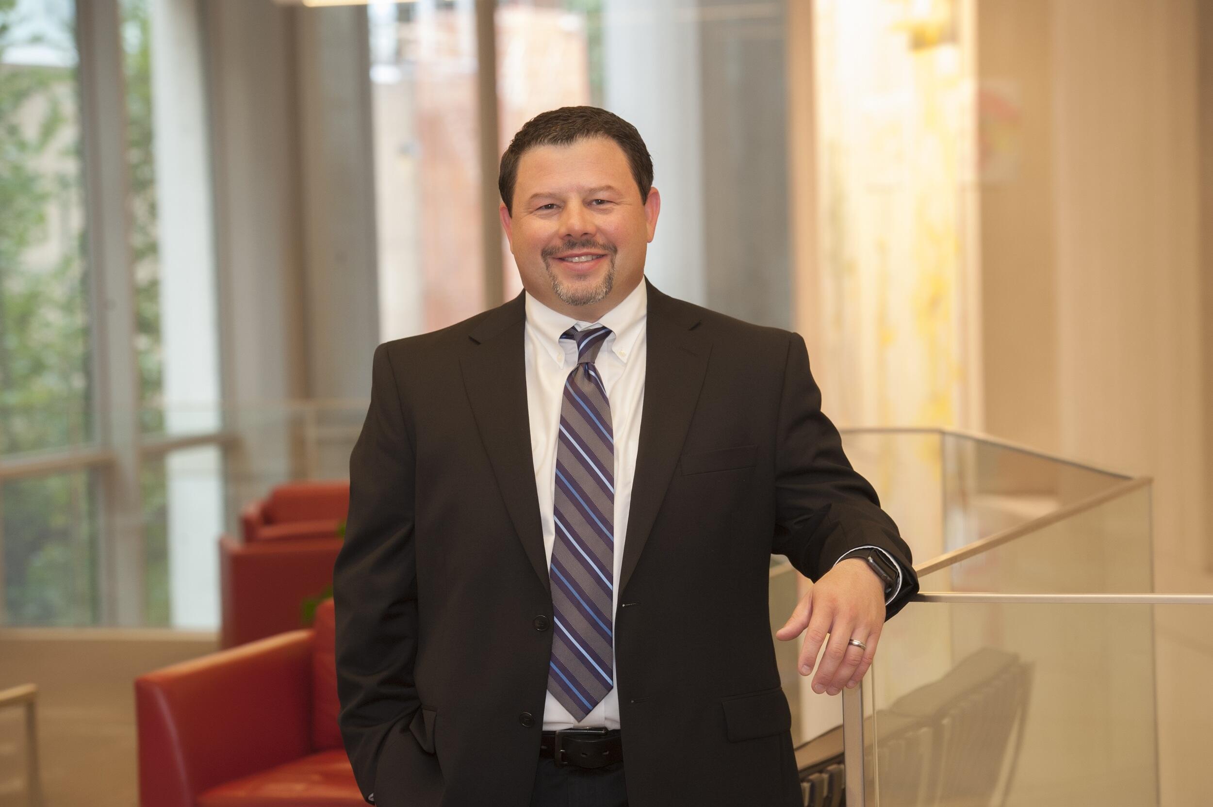 Bernard Fuemmeler standing and leaning on the railing of a glass divider 