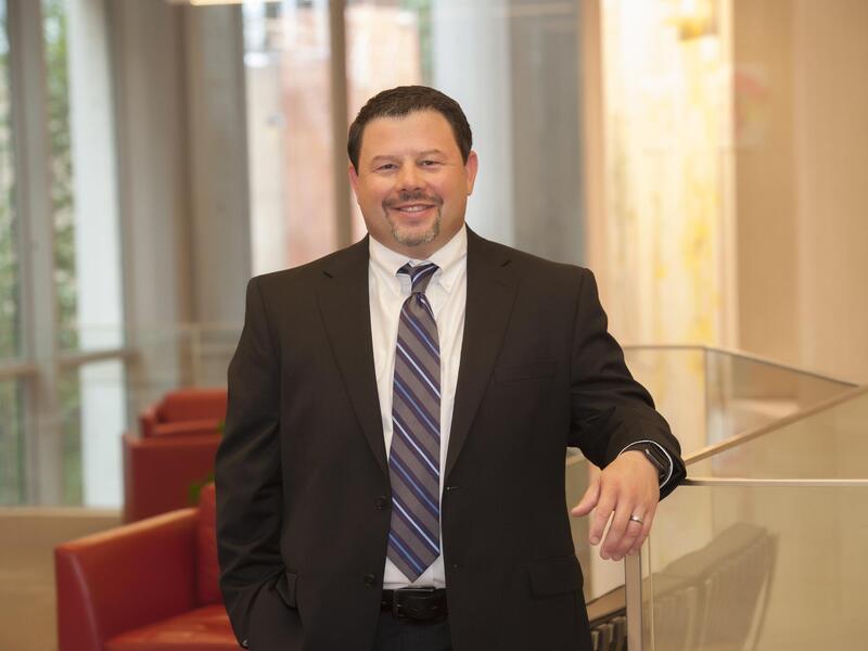 Bernard Fuemmeler standing and leaning on the railing of a glass divider 