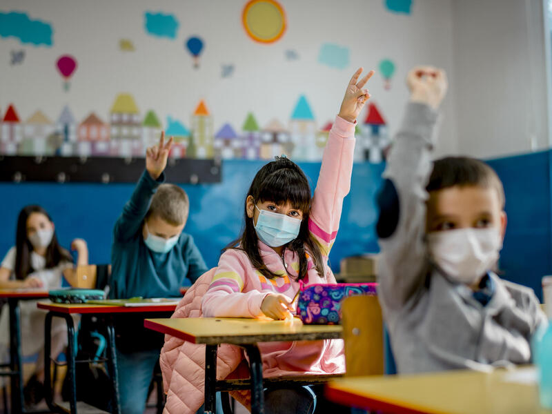 Elementary school children wearing a protective face masks in the classroom.