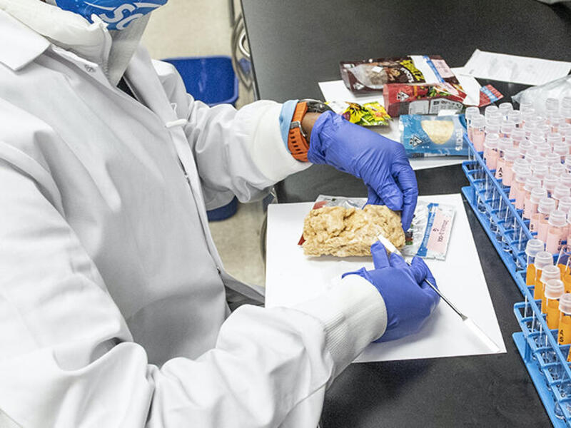 Amanda Moses Ferreira inside Michelle Peace's lab. Ferreira is removing a tiny sample from edibles advertised as containing delta-8