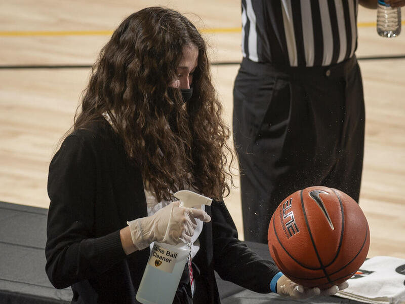 A VCU employee cleans a basketball during a game.