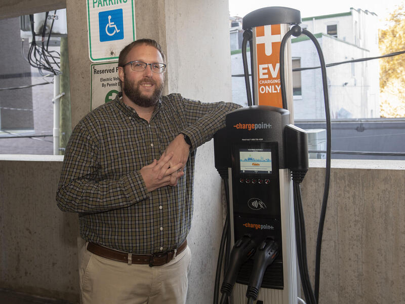 Josh Stone standing next to an electric vehicle charging station