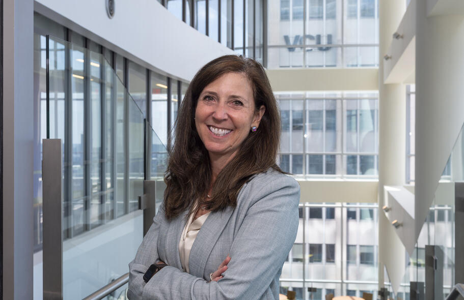 A portait of a smiling woman standing with her arms crossed against her chest. 