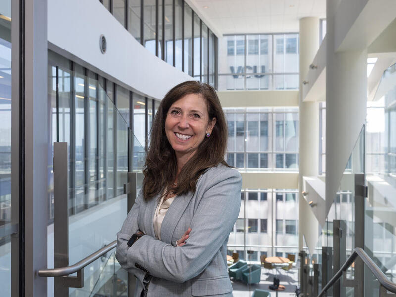 A portait of a smiling woman standing with her arms crossed against her chest. 