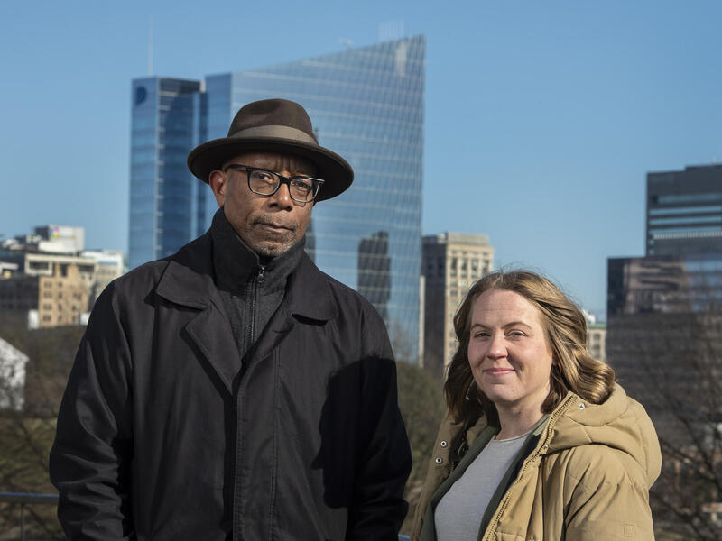 A photo of a man and a woman standing next to each other in front of the Richmond city skyline. 