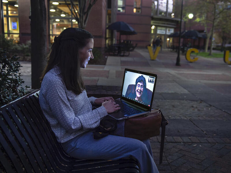 Student talks to friend using computer camera. 