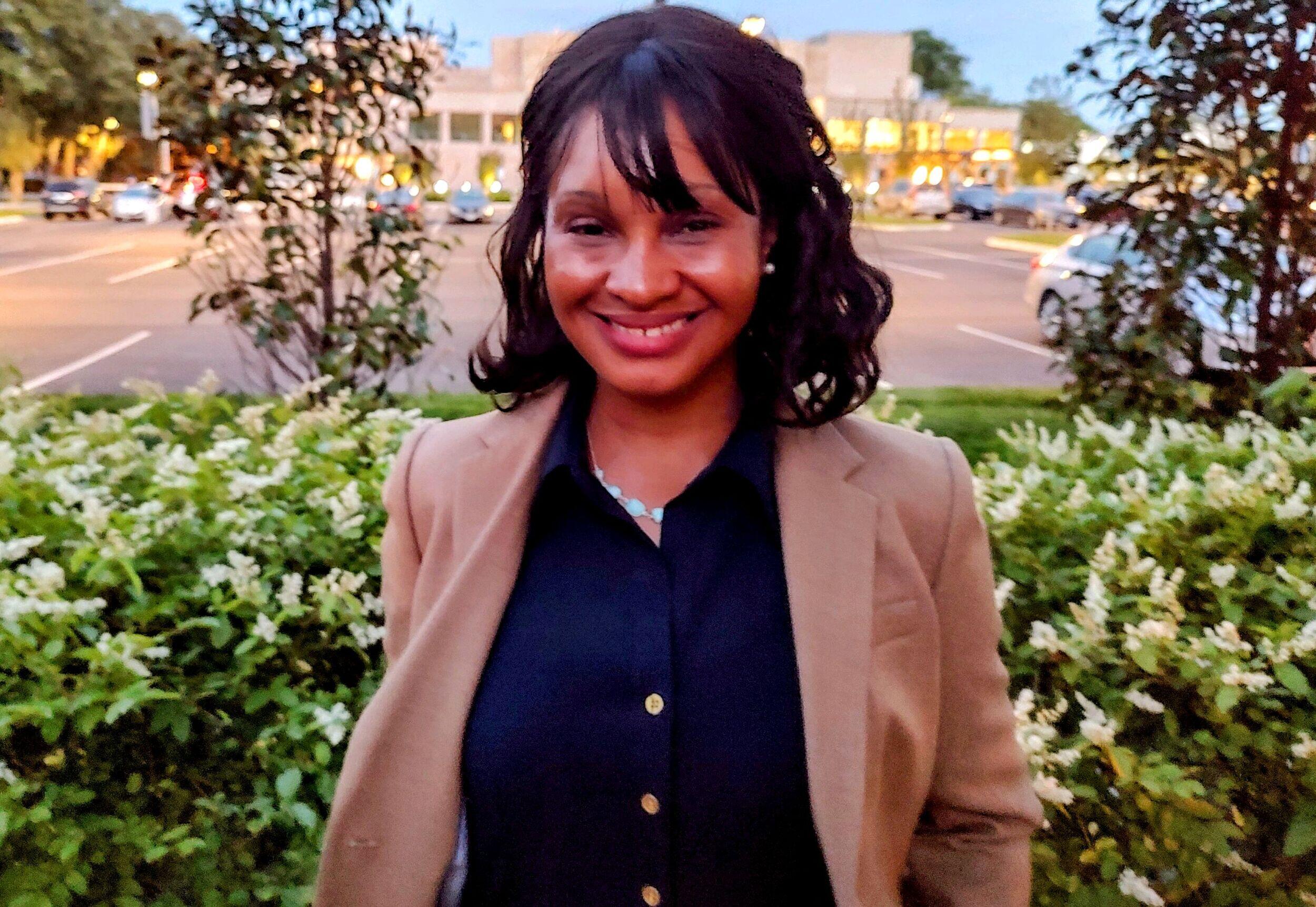 LaToya Gray-Sparks smiling at the camera standing in front of some bushes 