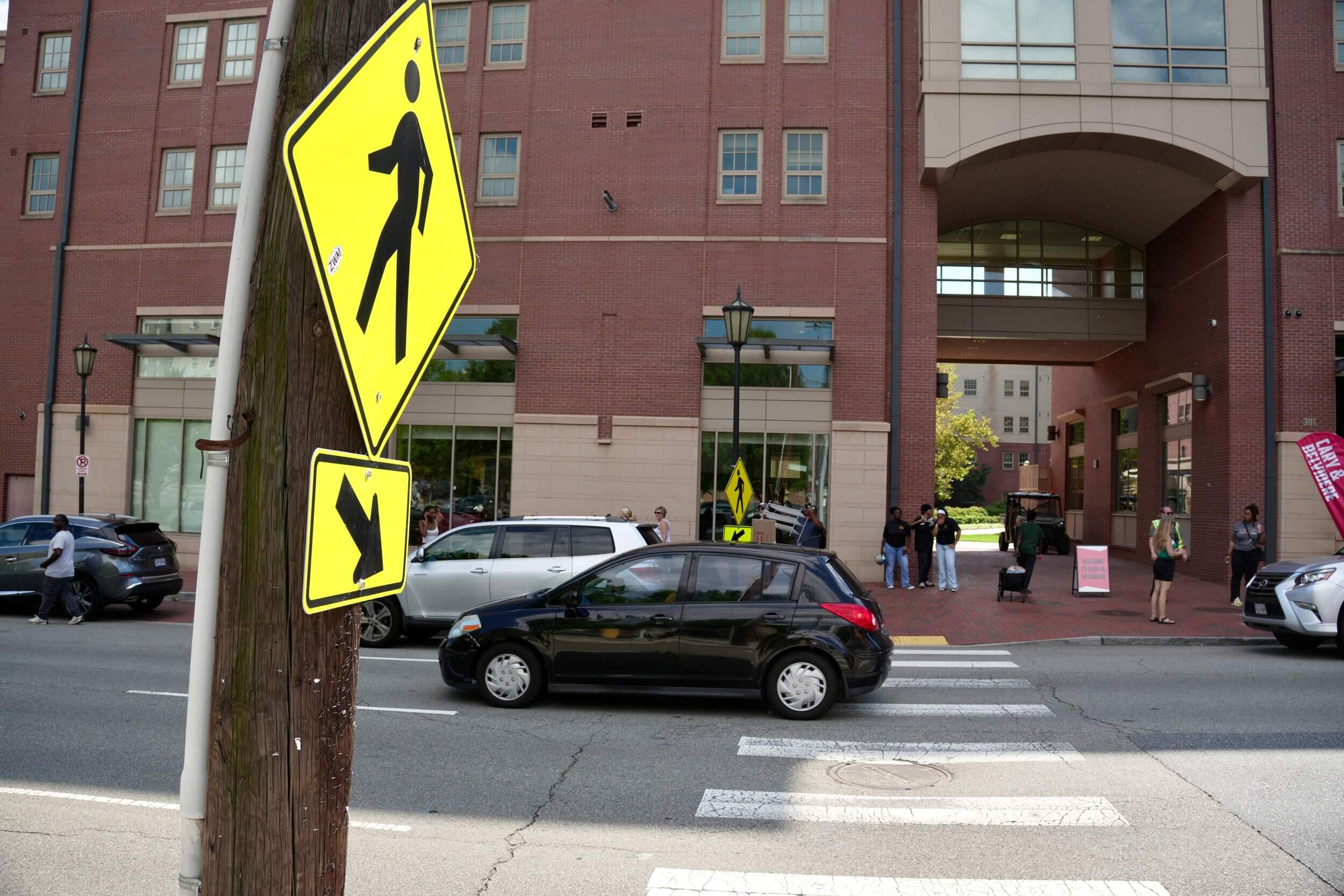 A photo of a cross walk with a cross walk sign next to it. 