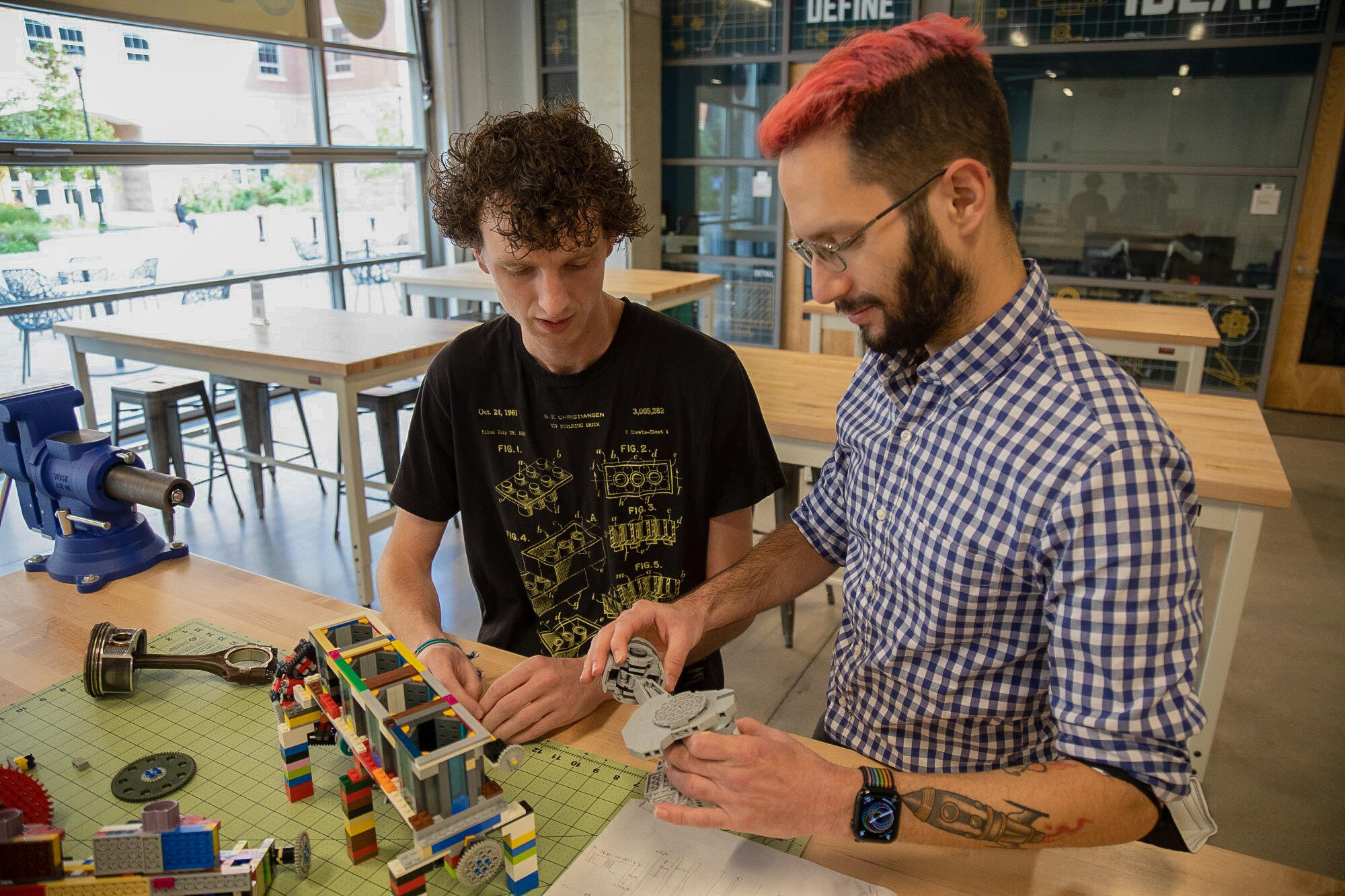 A student and a professor in a classroom work together building LEGOs.