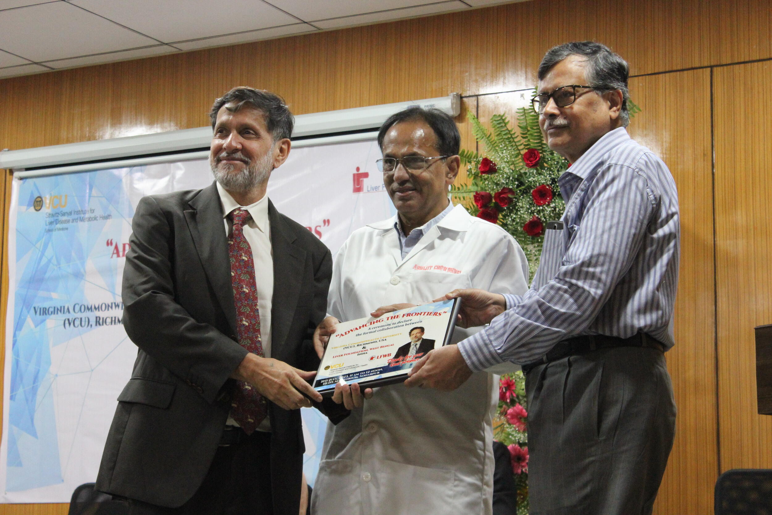 A photo of three men holding a piece of paper