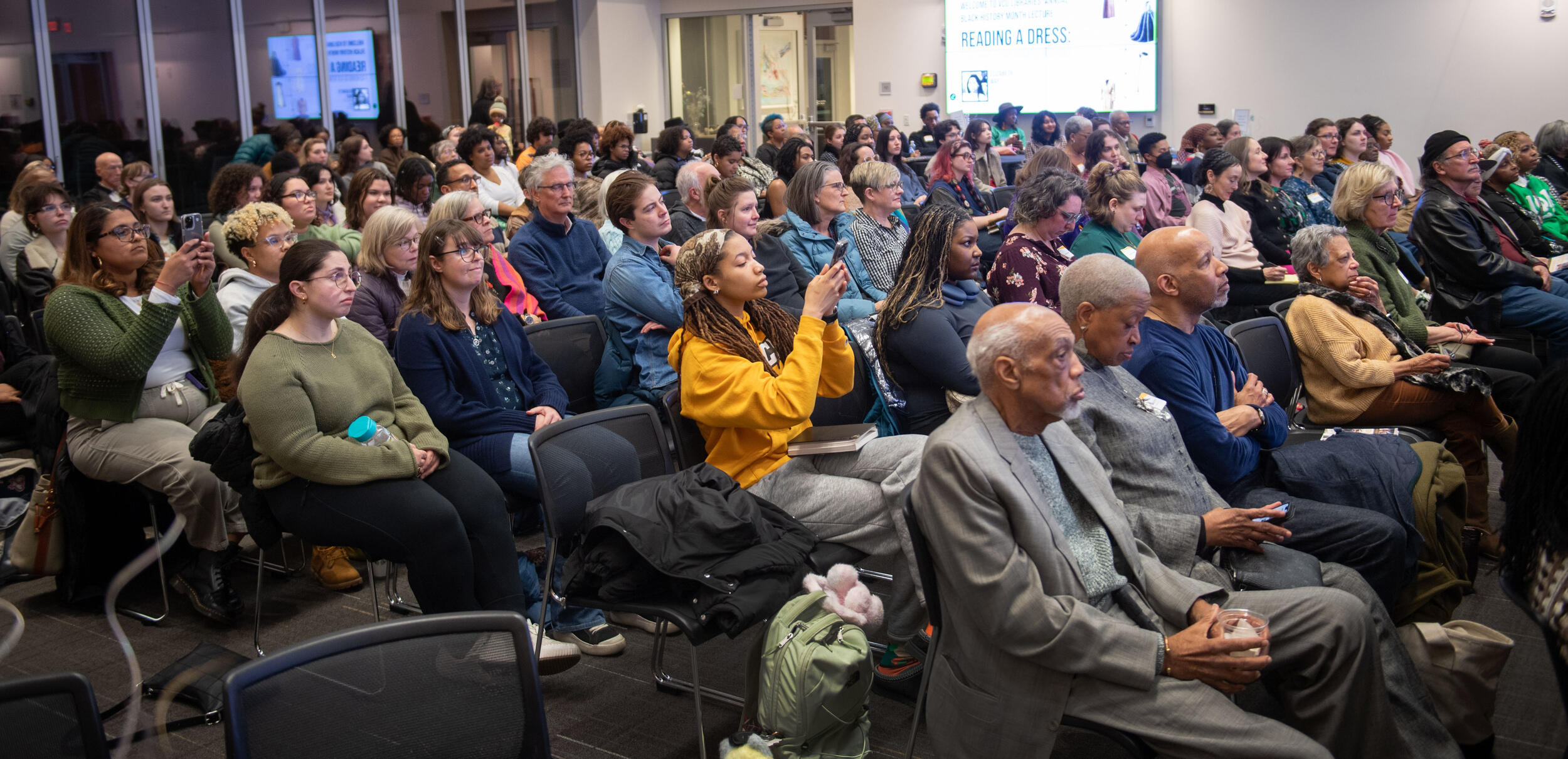 A photo of a crowd of people sitting in chairs. 