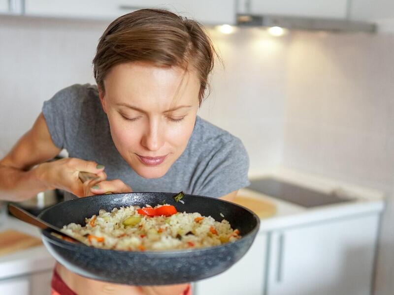 A person smells food cooking in a pan.