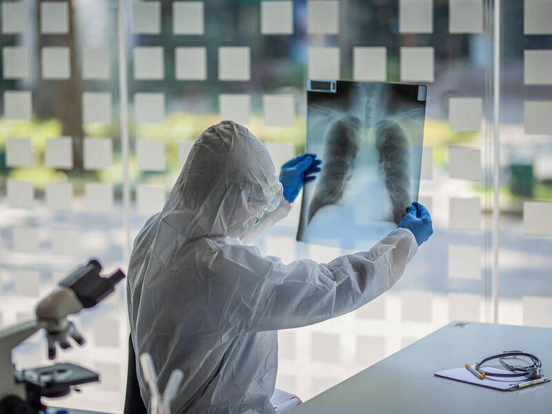 A person in personal protective gear holds an x-ray image.