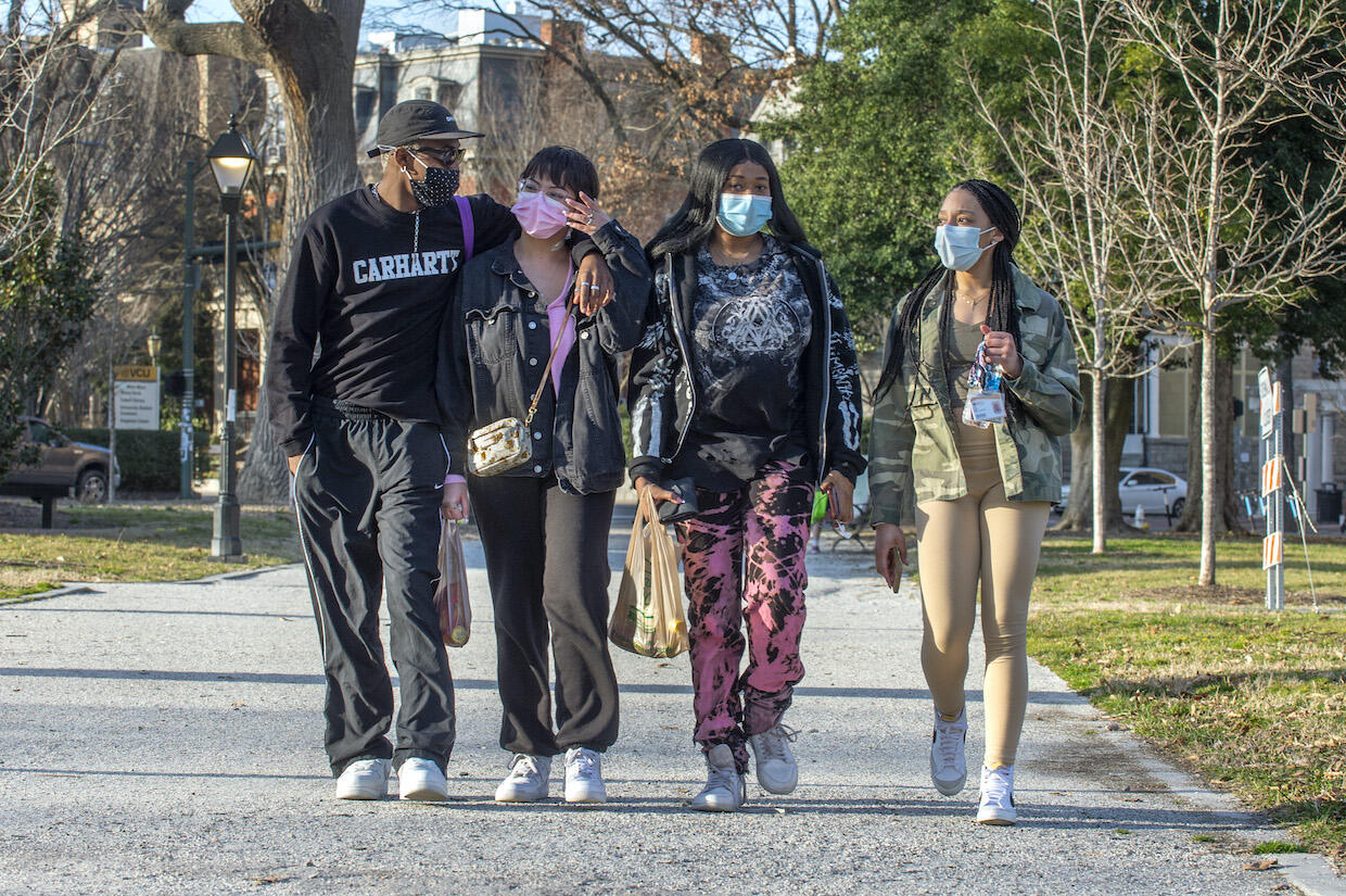 Four people walking through Monroe Park.