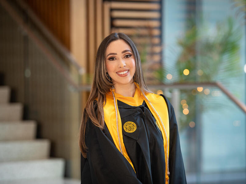 A portait of a woman wearing a graduation gown. 