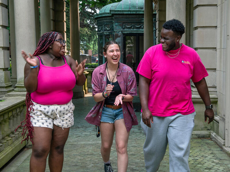 A photo of three people walking and laughing together. 