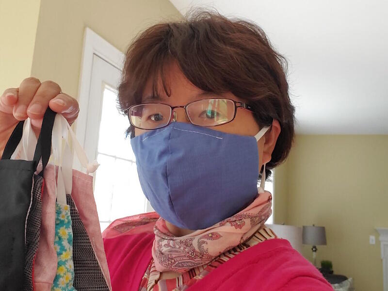 Woman wearing and holding a face mask. 