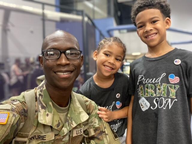 A man kneeling next to a young girl and boy