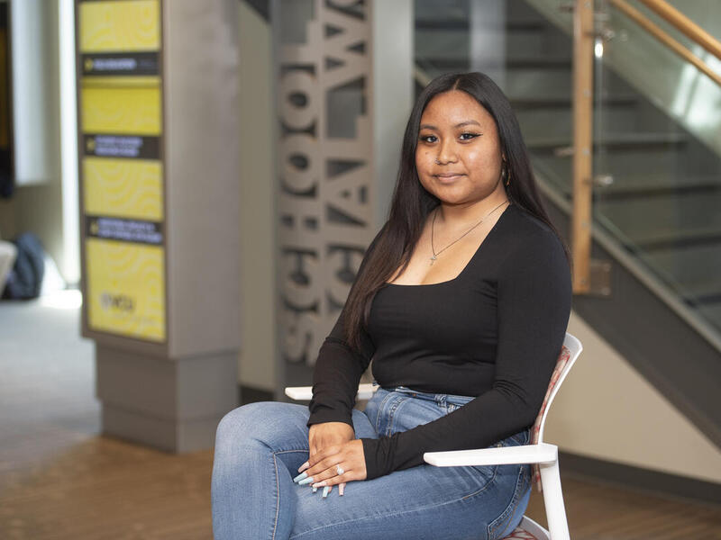 A photo of a woman in a long sleeve black shirt and blue jeans sittng in a chair. 