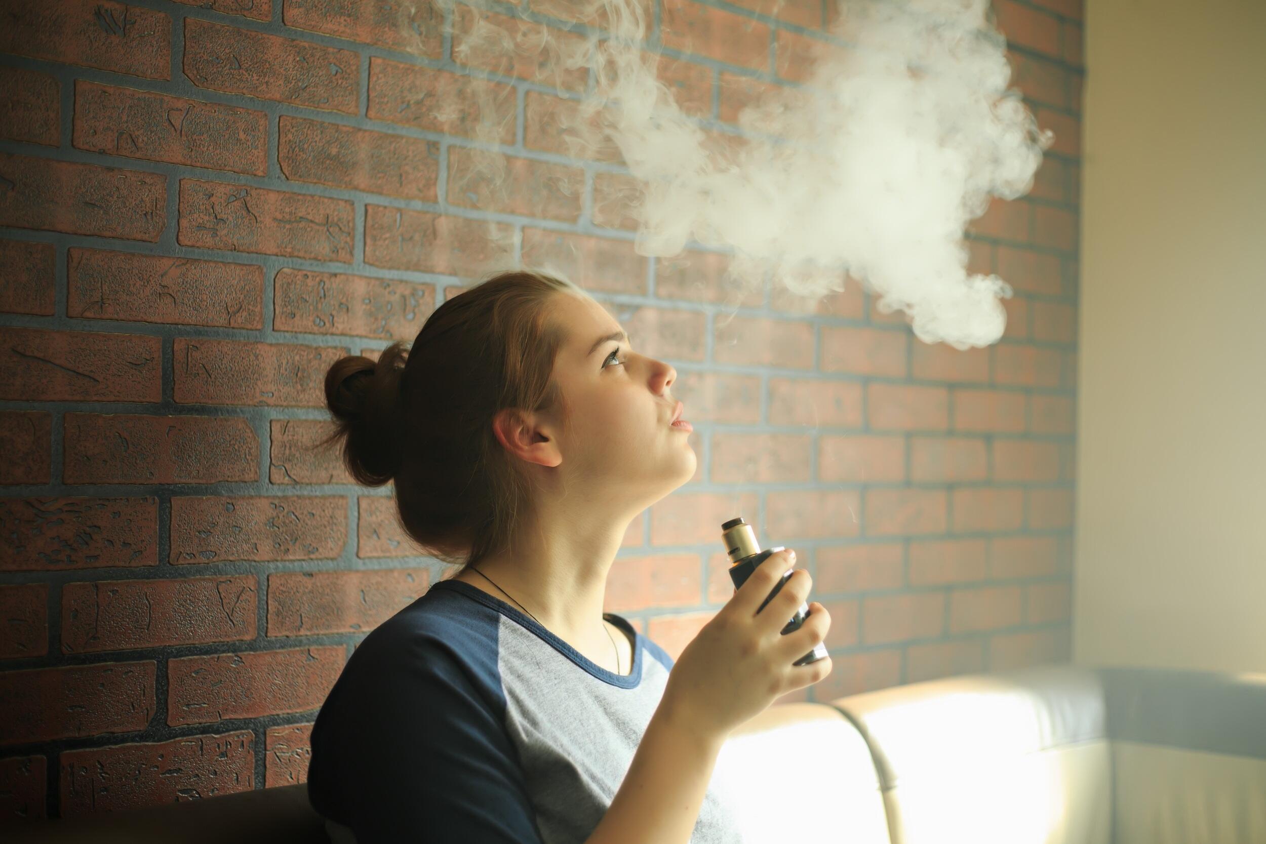 A user of an e-cigarette exhales vapor.