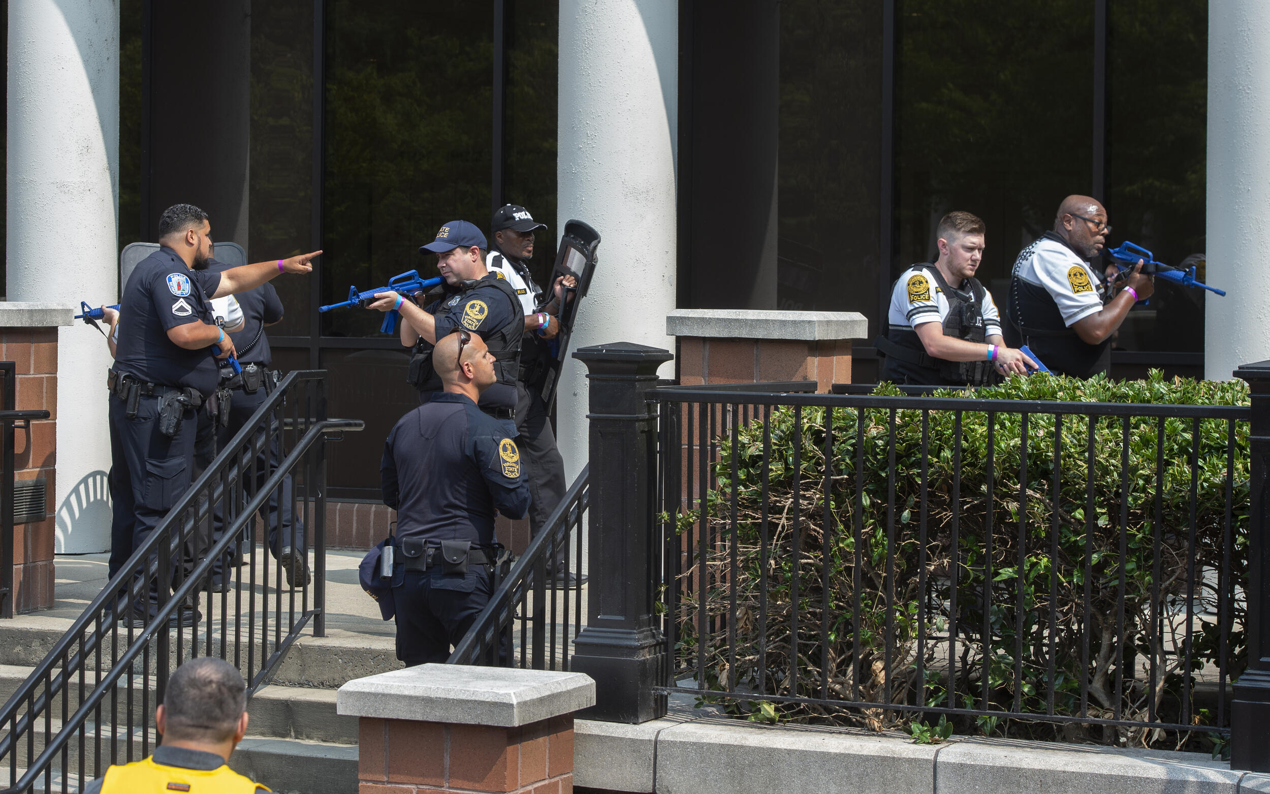 Police officers spread out around a set of stairs holding simulated weapons.