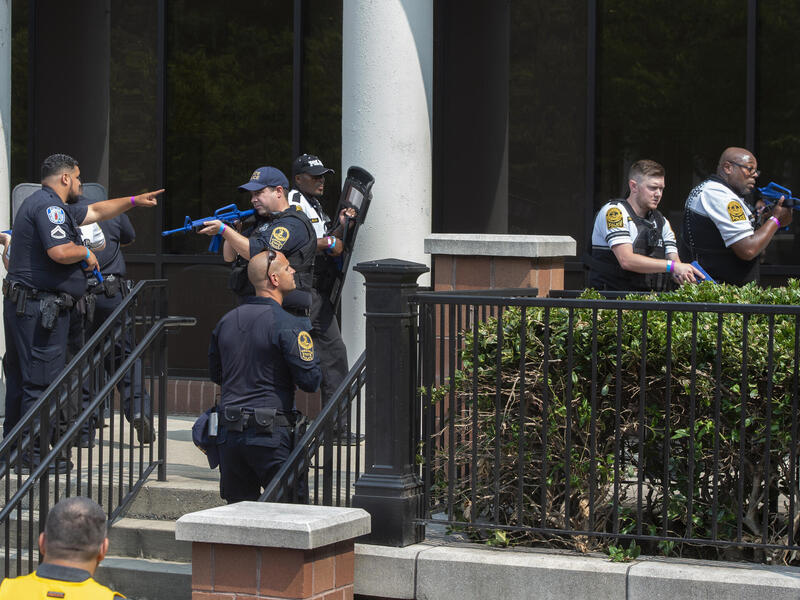 Police officers spread out around a set of stairs holding simulated weapons.