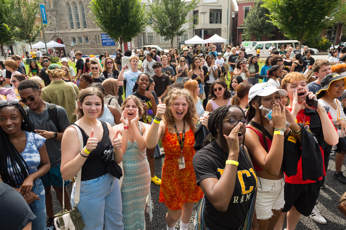 A crowd of students standing in monroe park, many of them are cheering. 