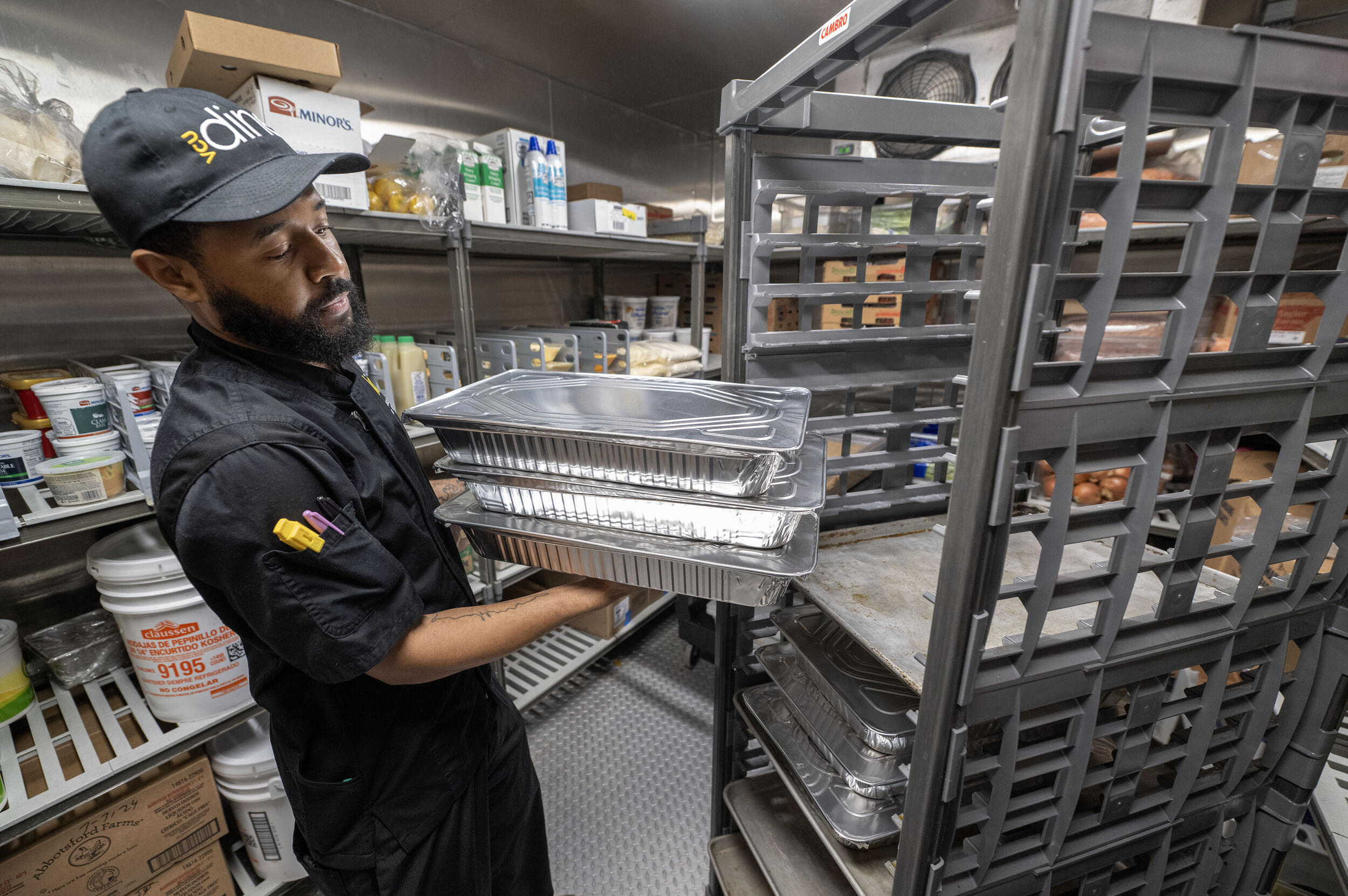 A photo of a man putting trays of food on a food cart