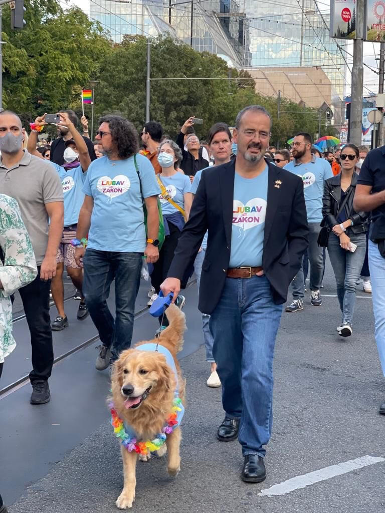 A photo of a man walking a dog in a crowd. 
