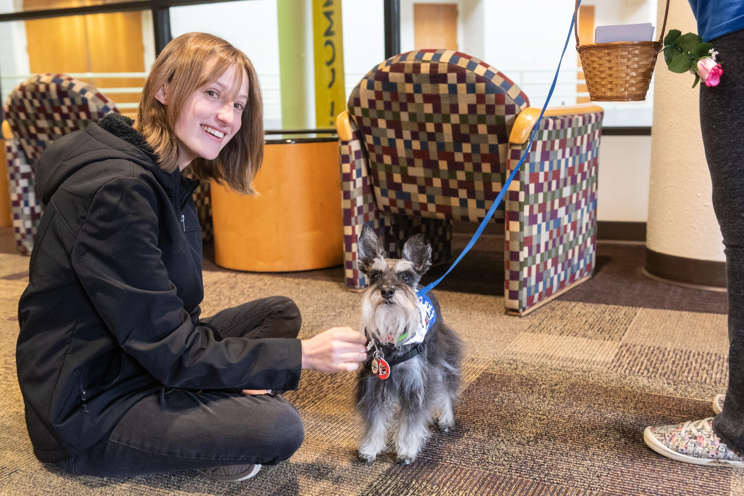 Woman sitting on the floor and petting a therapy dog.