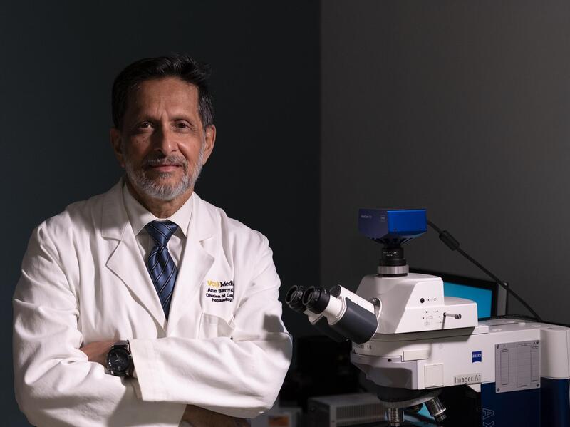 A man wearing a white lab coat with his arms crossed across his chest. 