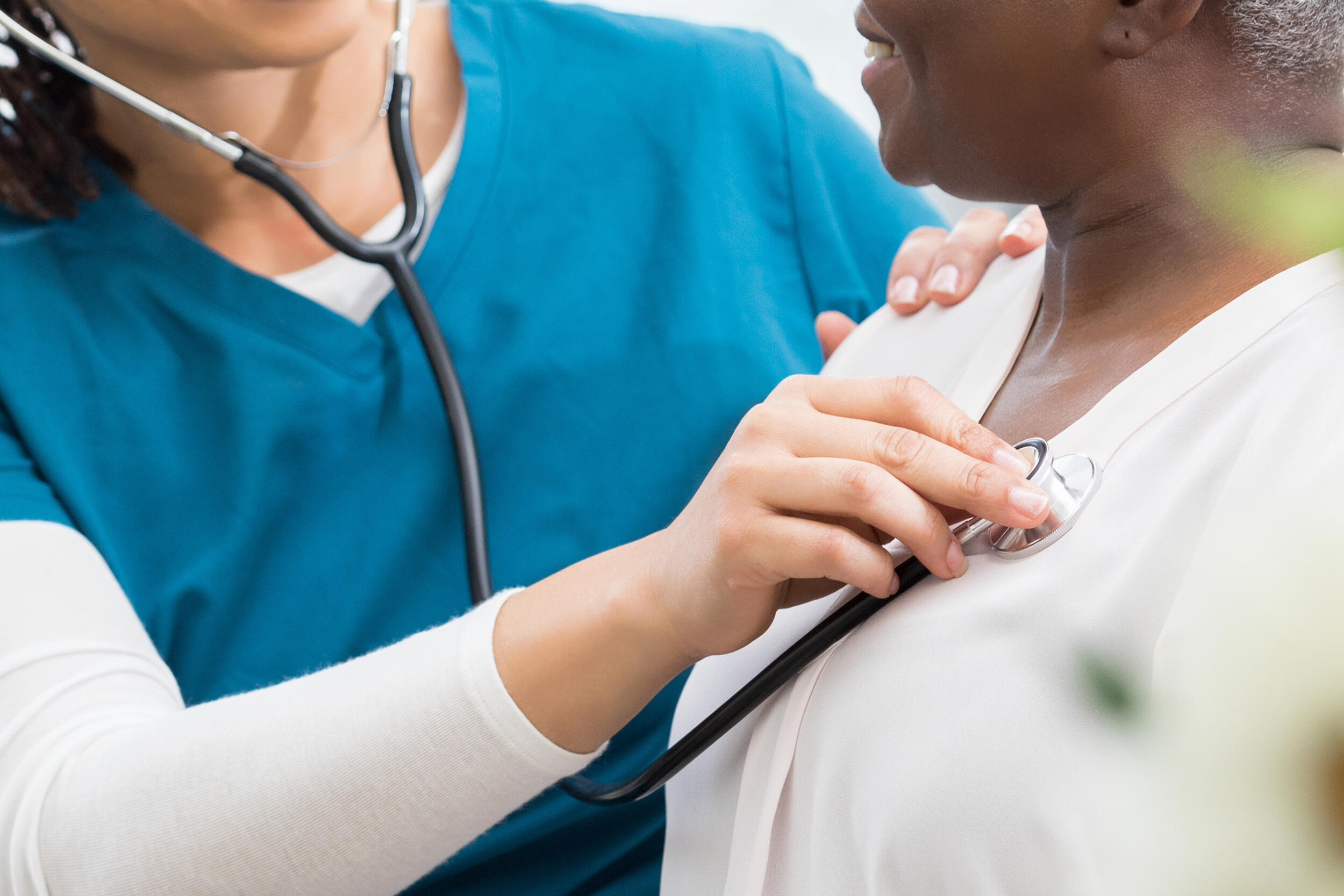 A photo of a medical professional listening to the heart beat of a patient. 
