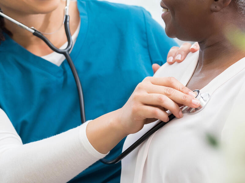 A photo of a medical professional listening to the heart beat of a patient. 