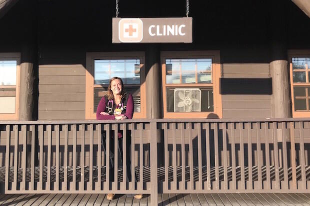 Woman standing at wood porch railing.