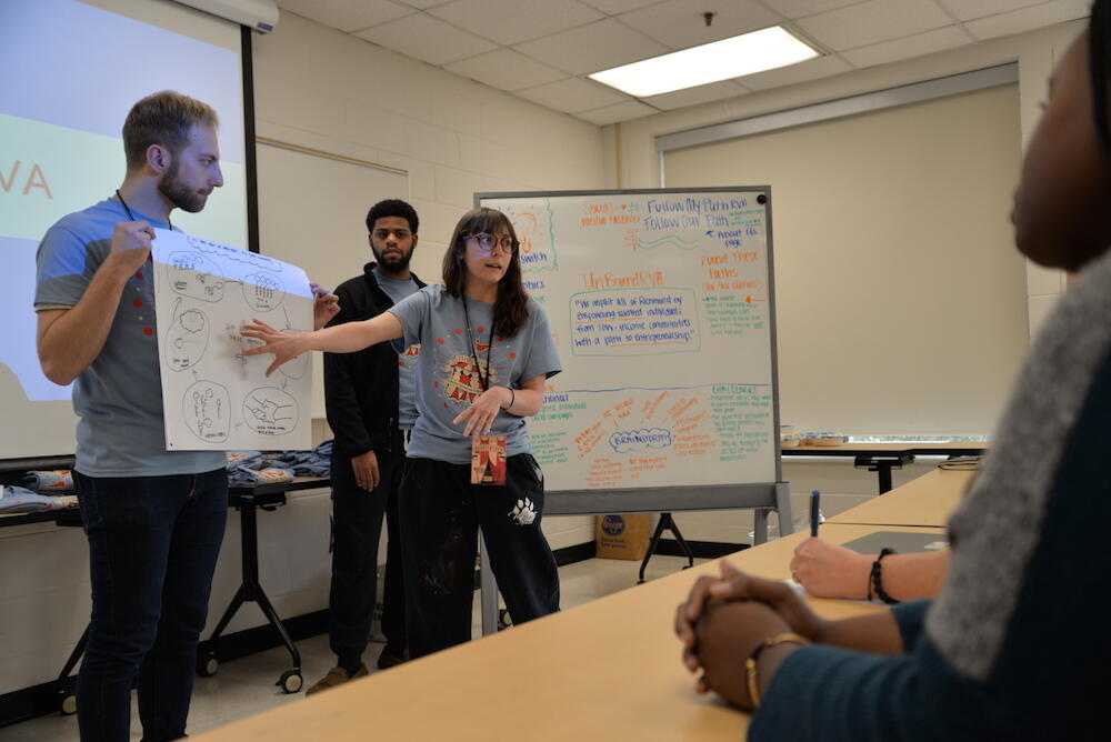 Jenna Thacker, a senior creative and strategic advertising major, shows early designs for an infographic for UnBoundRVA to a team of volunteer mentors on Thursday. (Photo by Brian McNeill, University Public Affairs)