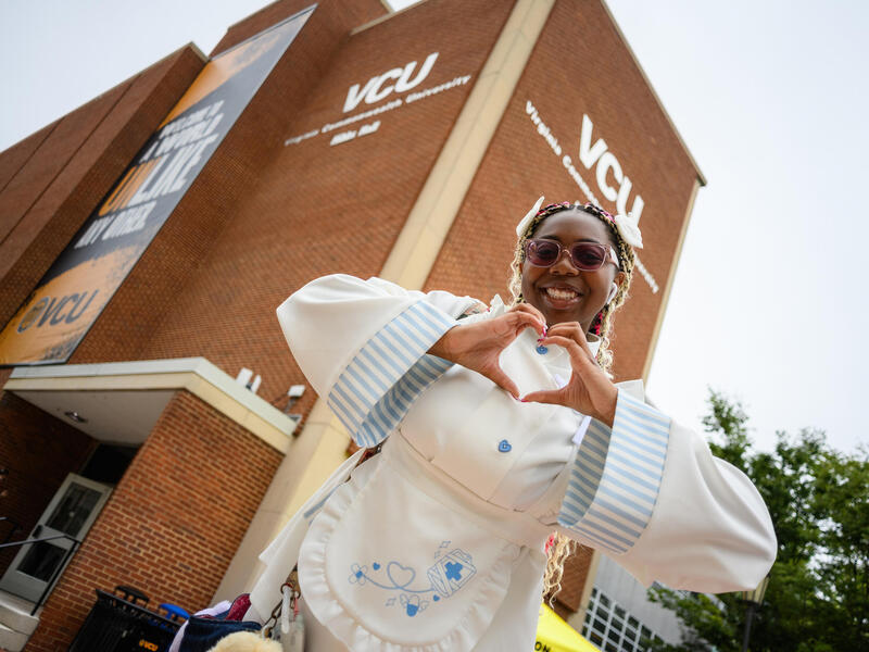 A photo of a woman making a heart with her hands. 