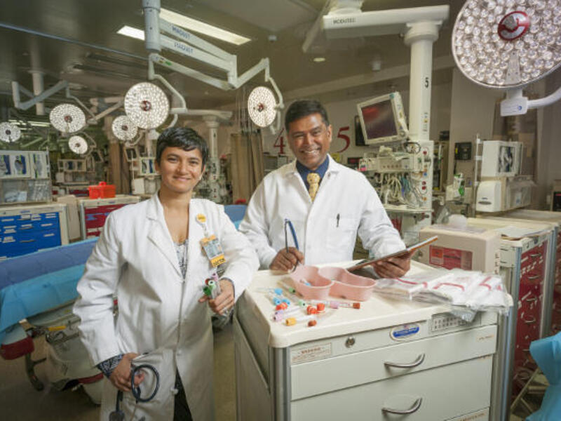 Two doctors in white coats stand in an operating room.