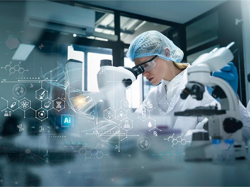 A photo of a woman looking into a microscope in a medical lab. 