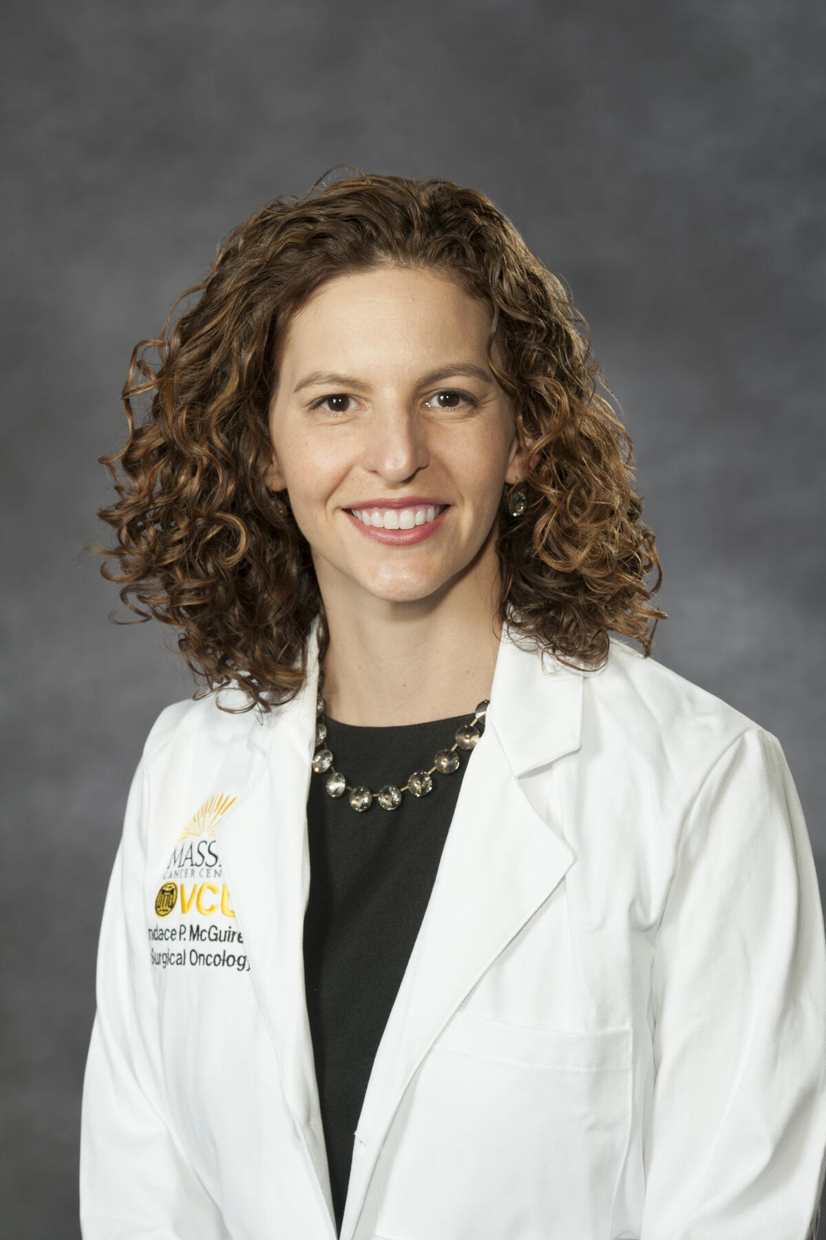 Smiling person wearing white doctor's coat.