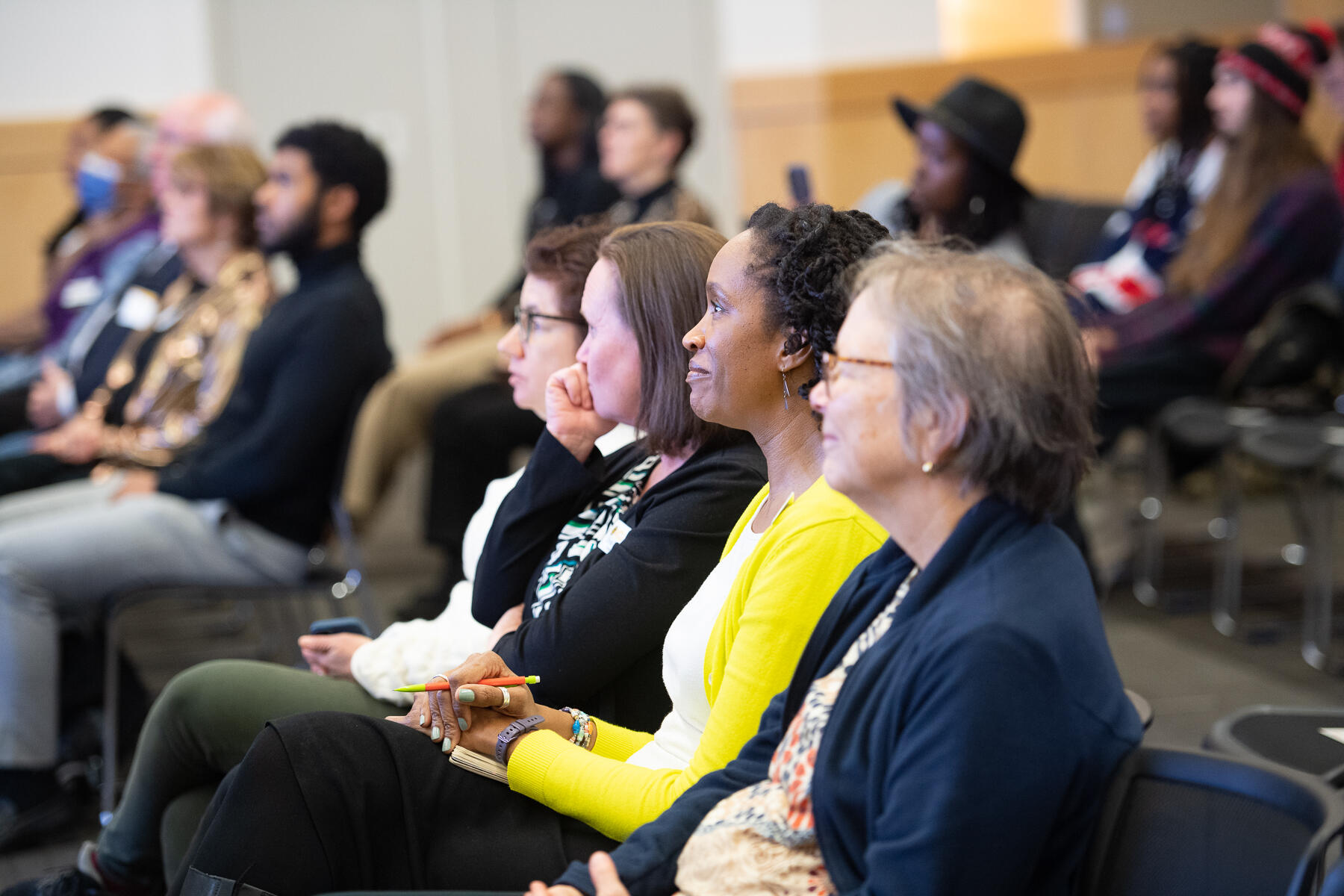 A photo of a crowd of people sitting in chairs and watching something. 