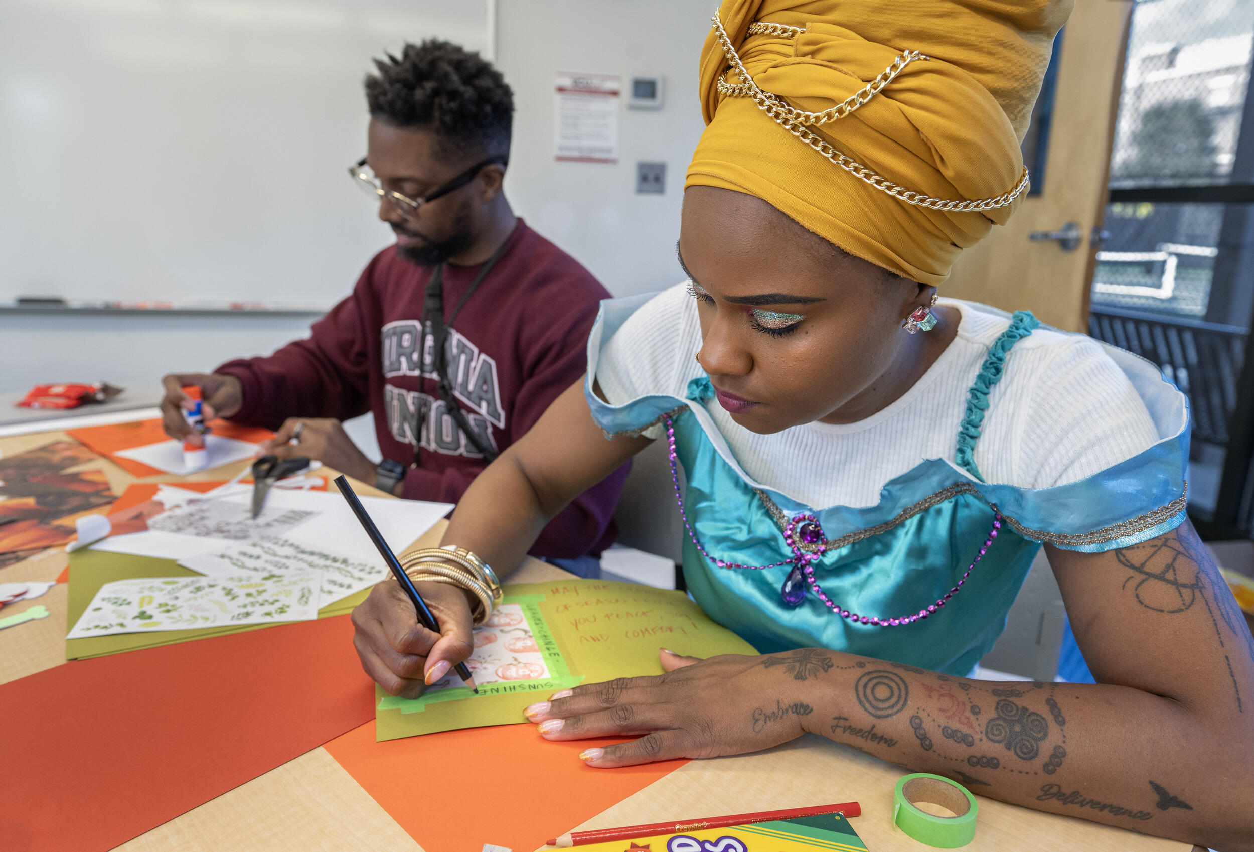 A photo of two people sitting at a table, writing on cards. 