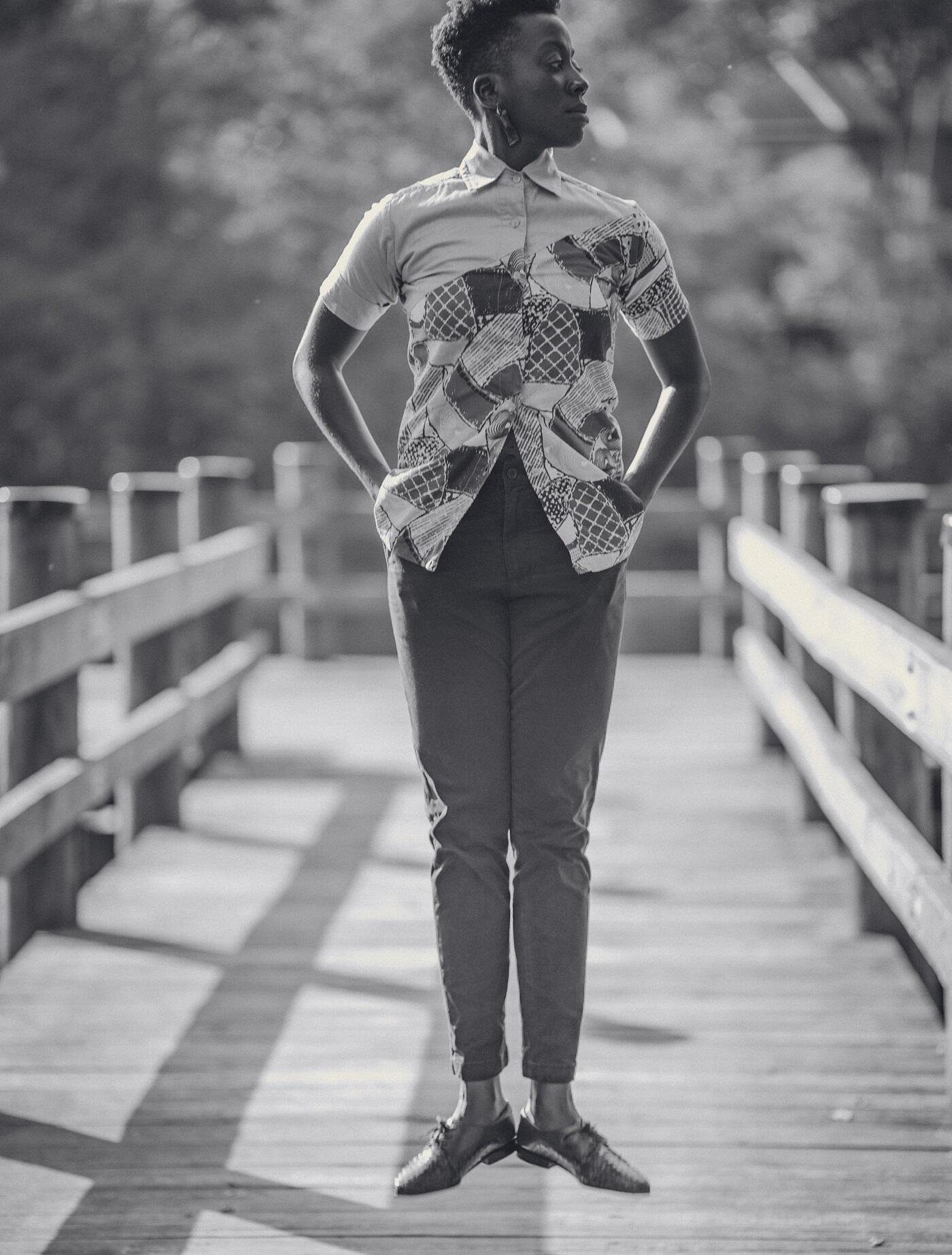 A black and white photo of a person with their hands in their pockets floating over a wooden walkway. 