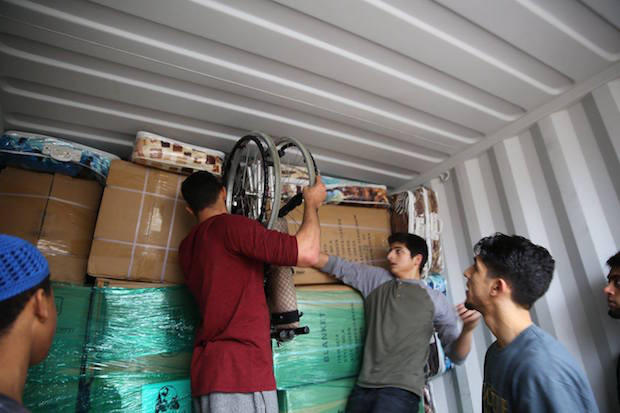 United2Heal volunteers stuff a wheel chair and blankets in between the boxes to utilize every inch of space in the container being shipped to Syria.