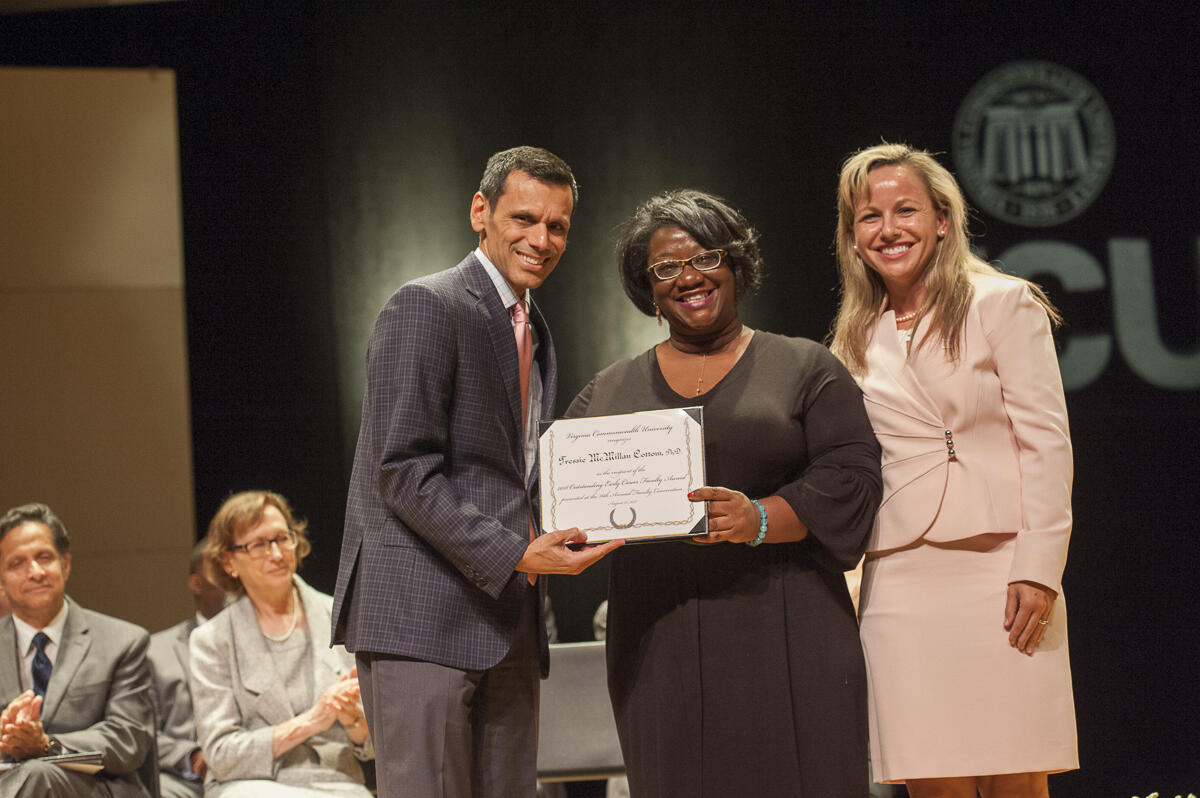 Tressie McMillan Cottom, Ph.D., middle, receives the Outstanding Early Career Faculty Award from VCU President Michael Rao, Ph.D., and Montse Fuentes, Ph.D., dean of the College of Humanities and Sciences. (Photo by Tom Kojcsich, University Relations)