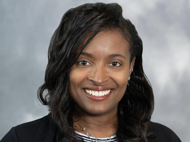 A woman wearing a sports coat and blouse smiling. 