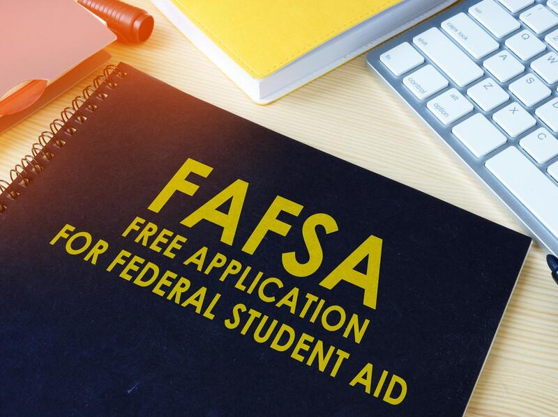 A photo of a black notebook sitting on a table. The front of the notebooks says \"FAFSA FREE APPLICATION FOR FEDERAL STUDENT AID\" in yellow letters