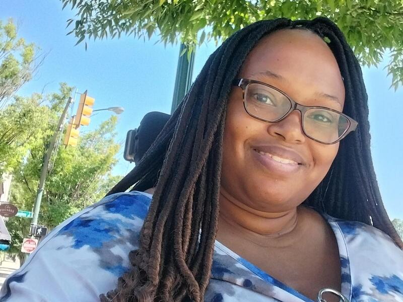 A photo of a woman wearing glasses smiling. 