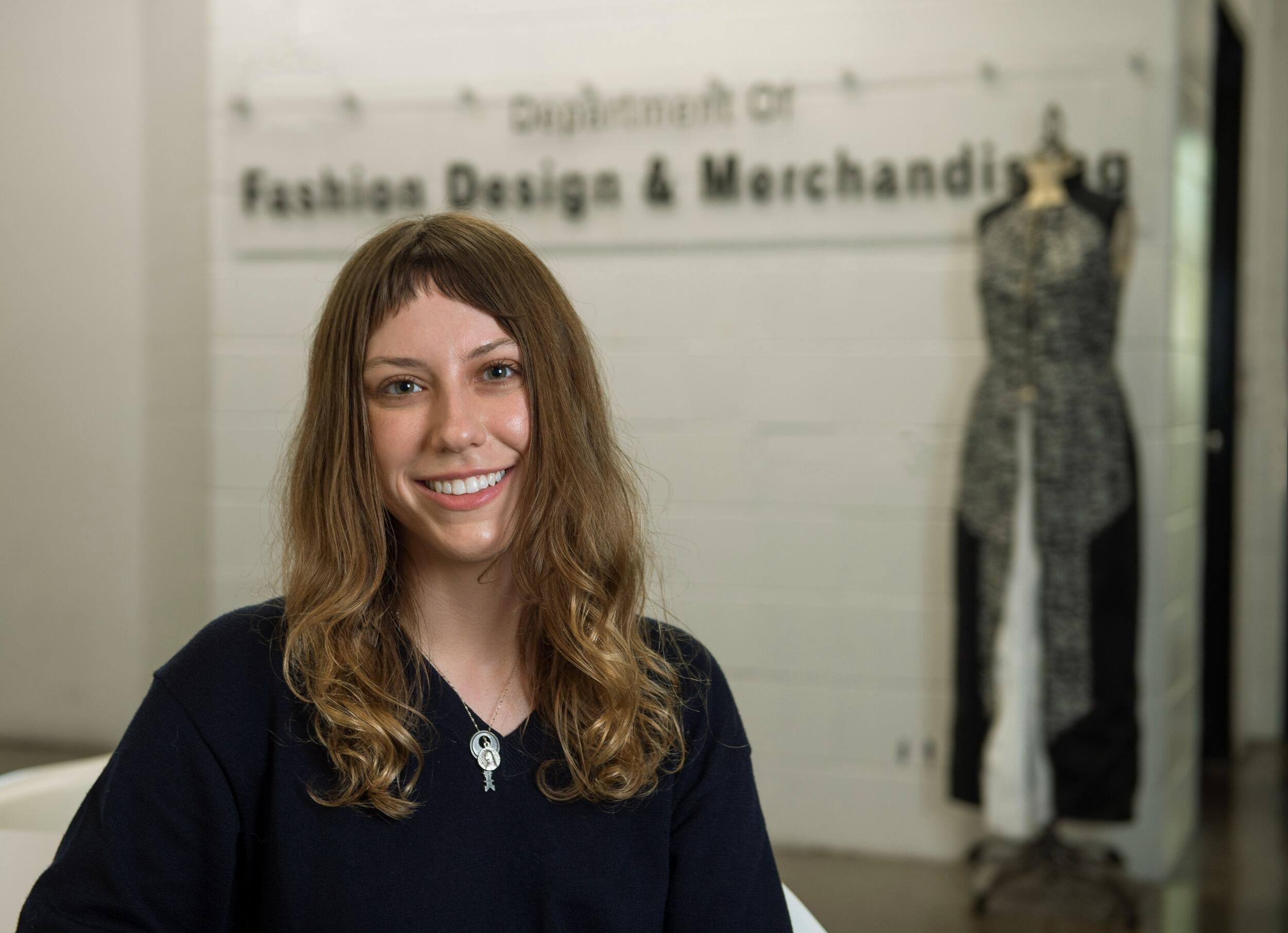 A photo of a woman standing in front of a maniquin. 