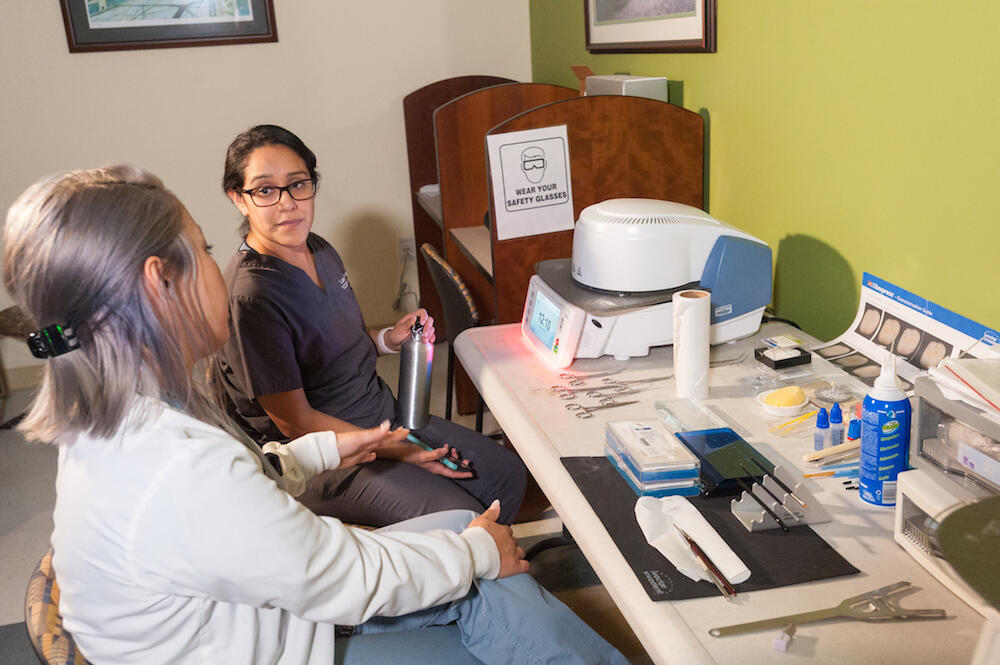 Front, Marithe Baclagon, digital lab technician, instructs a dentistry student on techniques for creating dental crowns. (Photo by Tom Kojcsich, University Relations)
